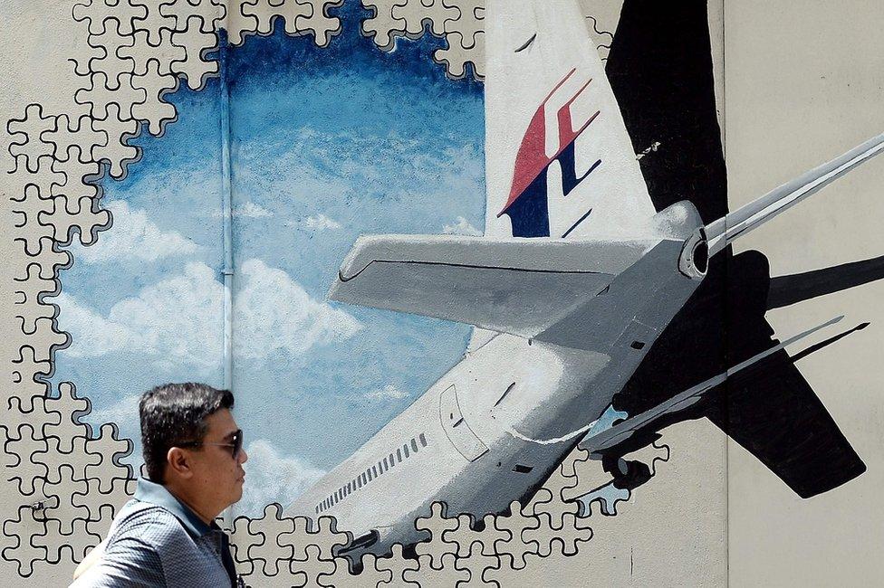 Picture taken on 8 March 2016 shows a man walking in front of a mural of missing MH370 in a back-alley in Kuala Lumpur.