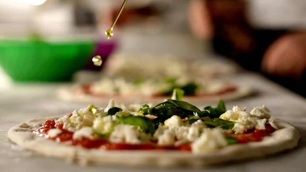 A pizza maker prepares a pizza