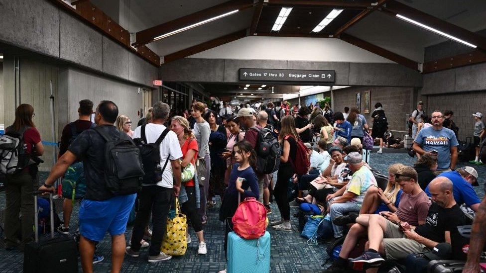 tourists wait at the airport to try and leave the island