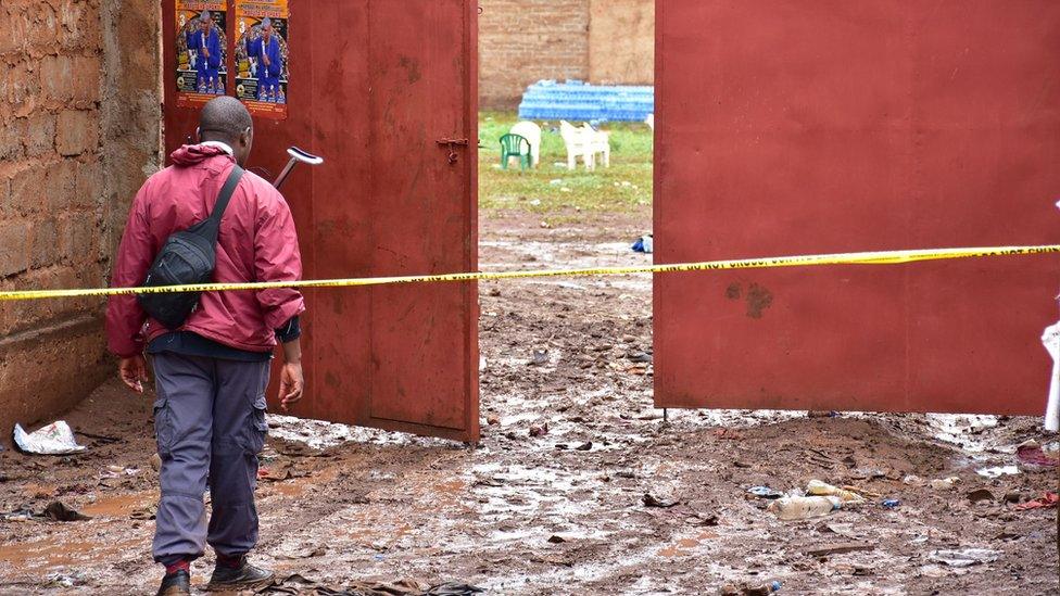 A plainclothes officer guards the entrance to the scene