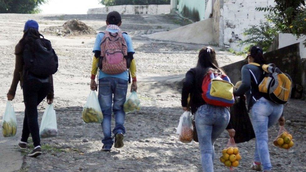 Marlon Carrillo (2nd L) and his relatives carrying bags with fruits bought in Venezuela, walk on the street as they look for clients in Cucuta, Colombia December 15, 2017.