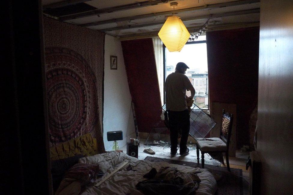 A man holding a window pane in a darkened room