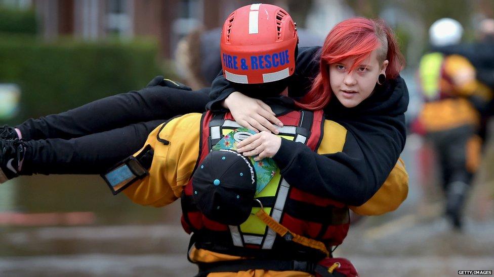 A member of rescue team helps a young woman in Carlisle