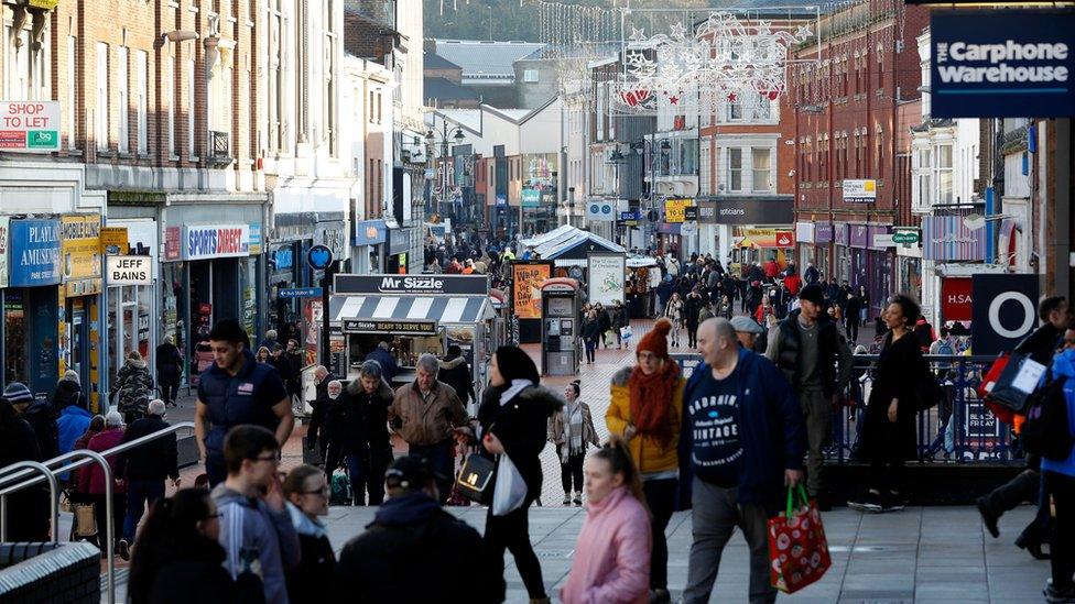 Shoppers walk in the town centre of Walsall on November 29, 2019