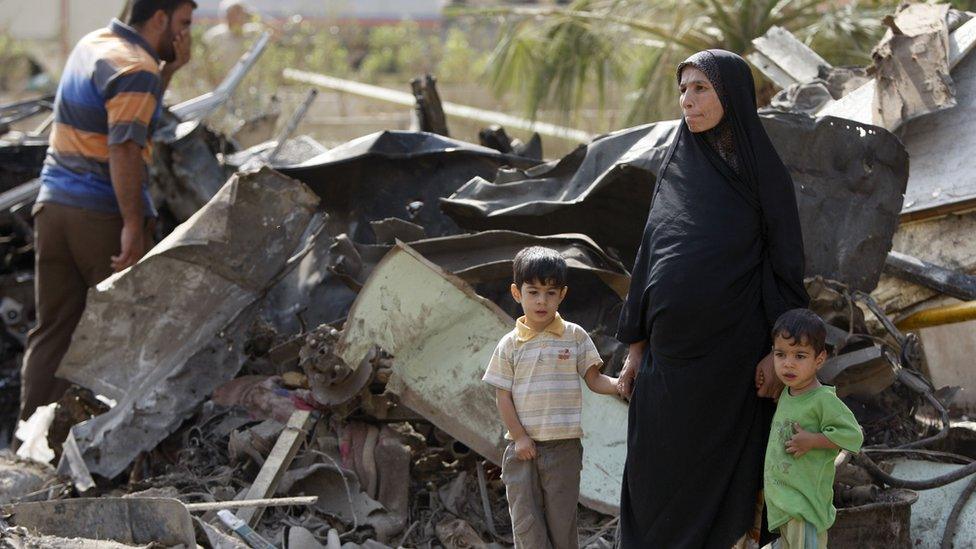 An Iraqi woman and her boys survey the damage after October 2009 bomb attacks in Baghdad.