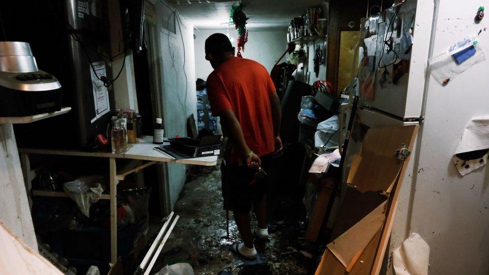 A resident walks through his flooded basement level apartment in a Queens neighbourhood