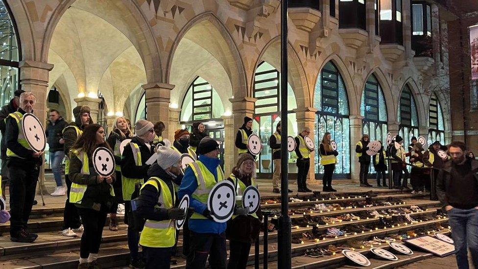 Campaigners in yellow hi-viz stand on the Guildhall steps