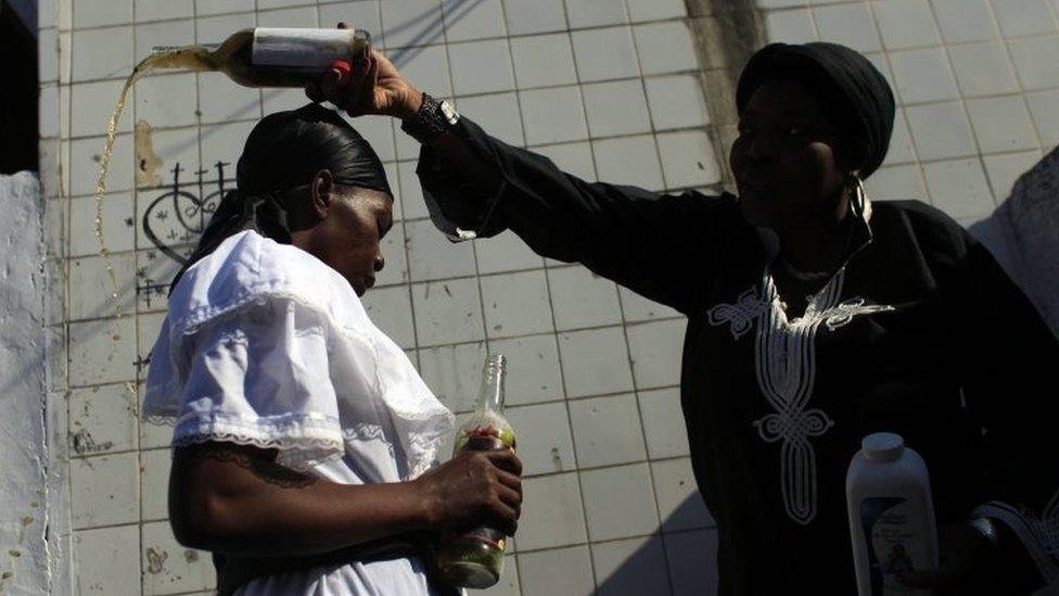 Two women participate in a Voodoo ritual in tribute to Baron Samdi and the Gede family of spirits during Day of the Dead celebrations at the National Cemetery in Port-au-Prince on 1 November, 2015.