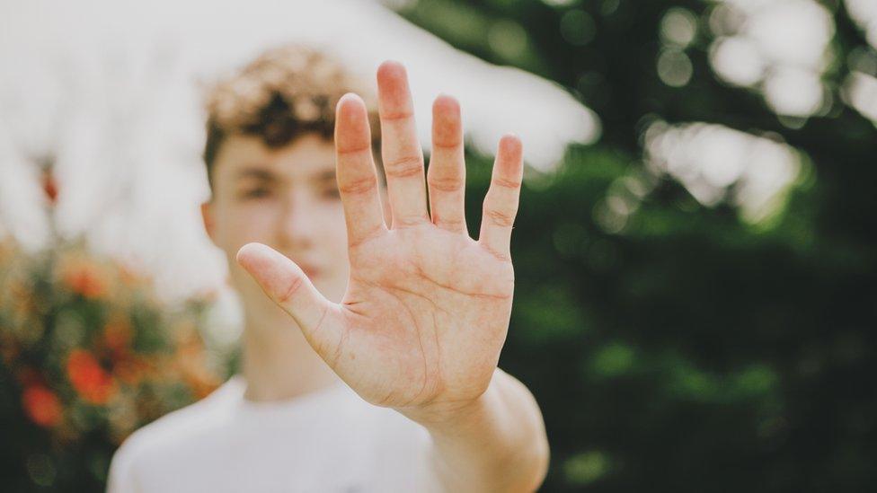 Young man holds up hand in "stop" motion