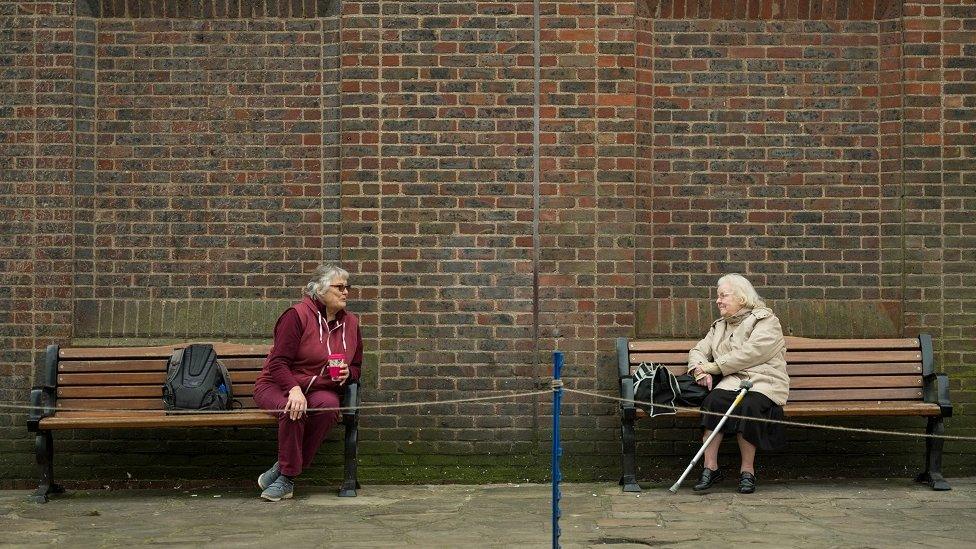 Two women observe social distancing measures