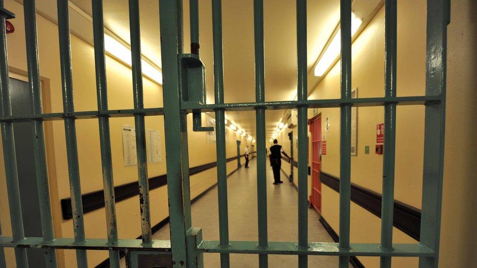 A prison corridor seen through a barred gate