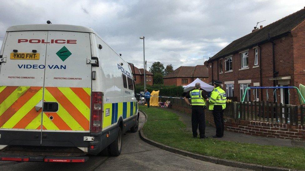 Police van and officers standing outside the scene of a house fire