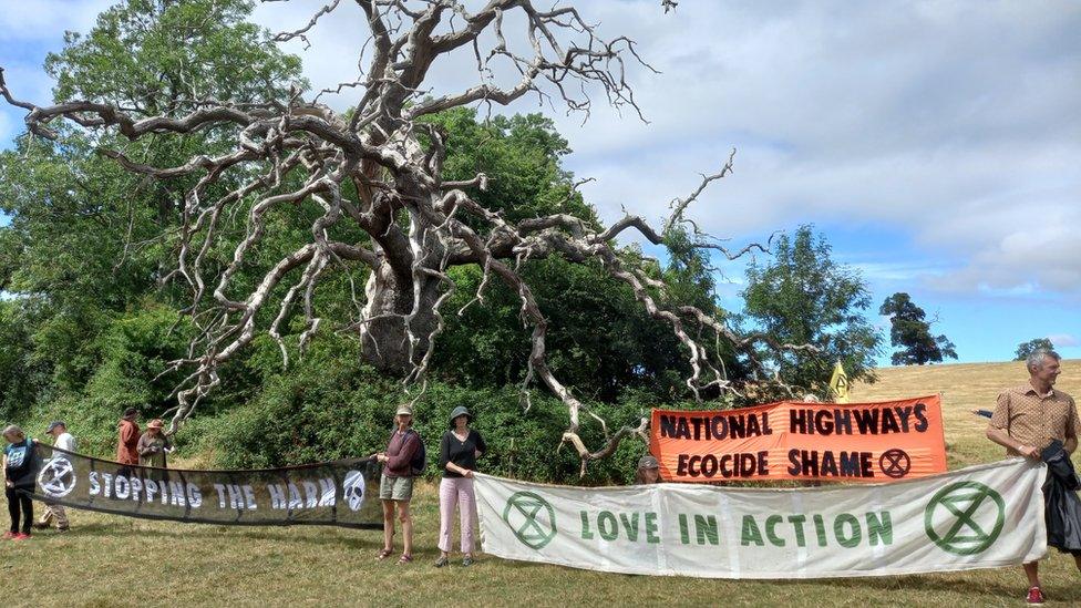 Banners reading love in action and stopping the harm by the tree