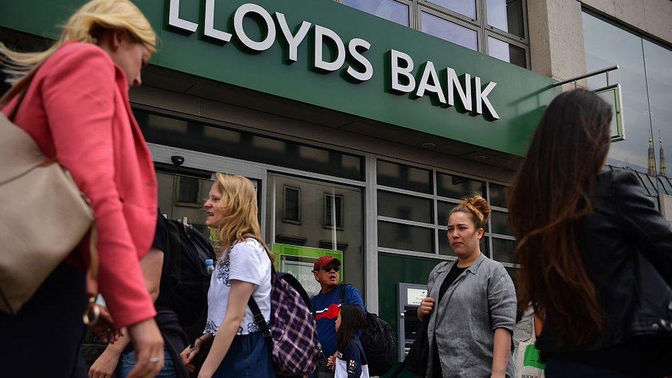 People walk past a branch of Lloyds Bank