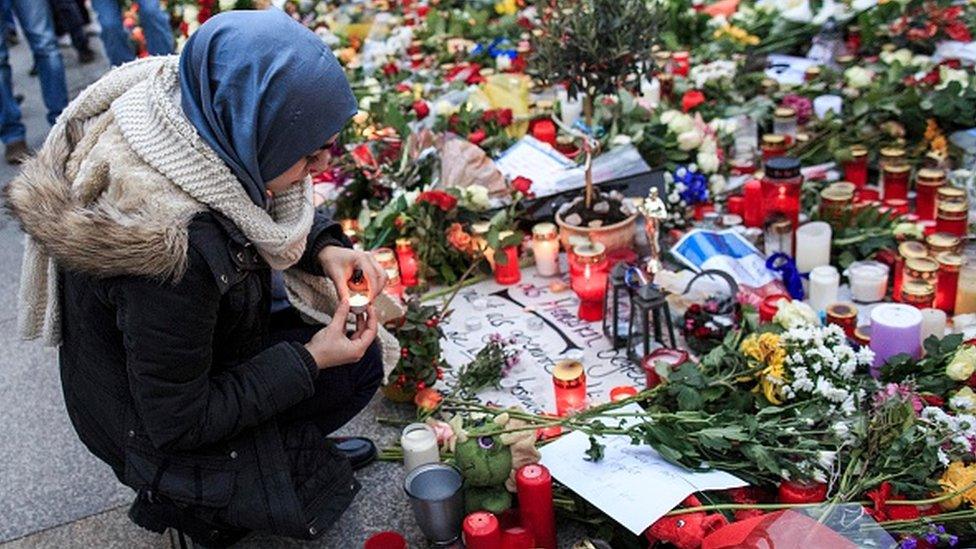 A young Muslim woman lights a candle outside the French Embassy in Berlin