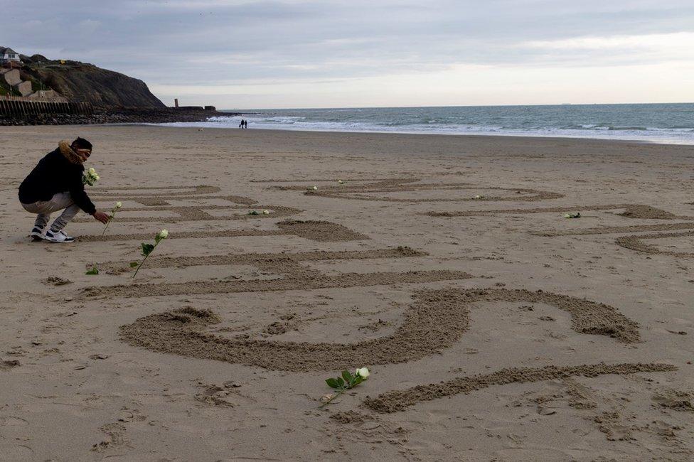 A man lays flowers on the beach