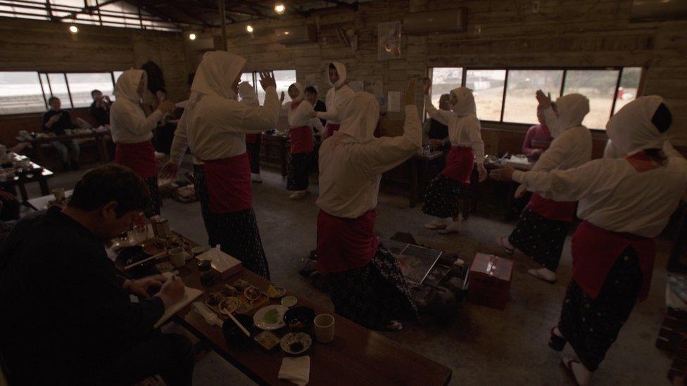 Japanese female divers putting on a dance performance for tourists