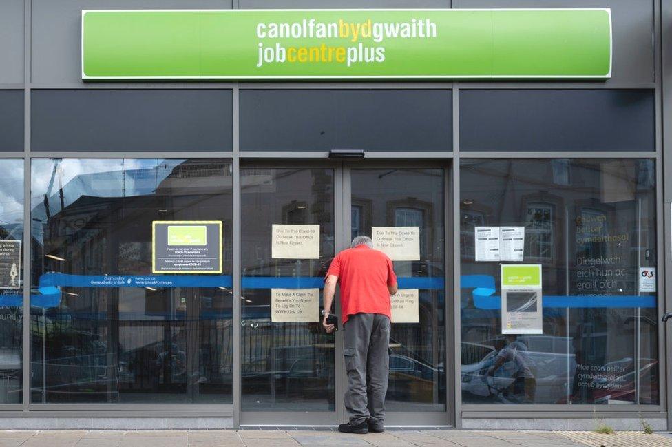 Dyn yn edrych drwy ffenestr Job Centre Plus yn Bargoed