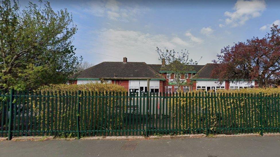 Outside of Tennyson Road School seen behind a green metal fence