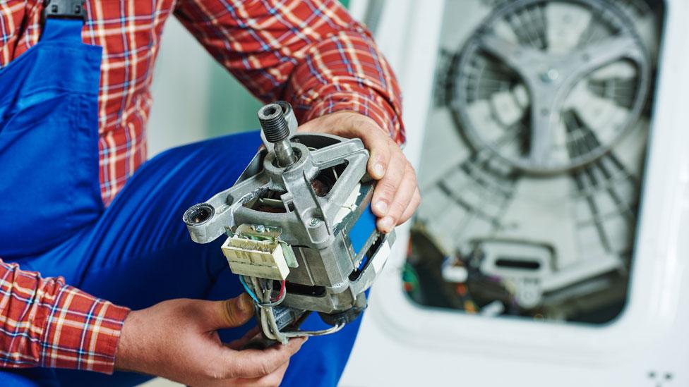 A man with an engine in front of a washing machine