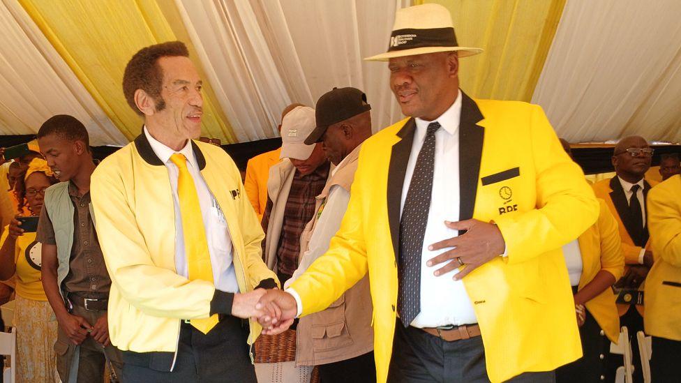 Two men dressed in yellow shaking hands