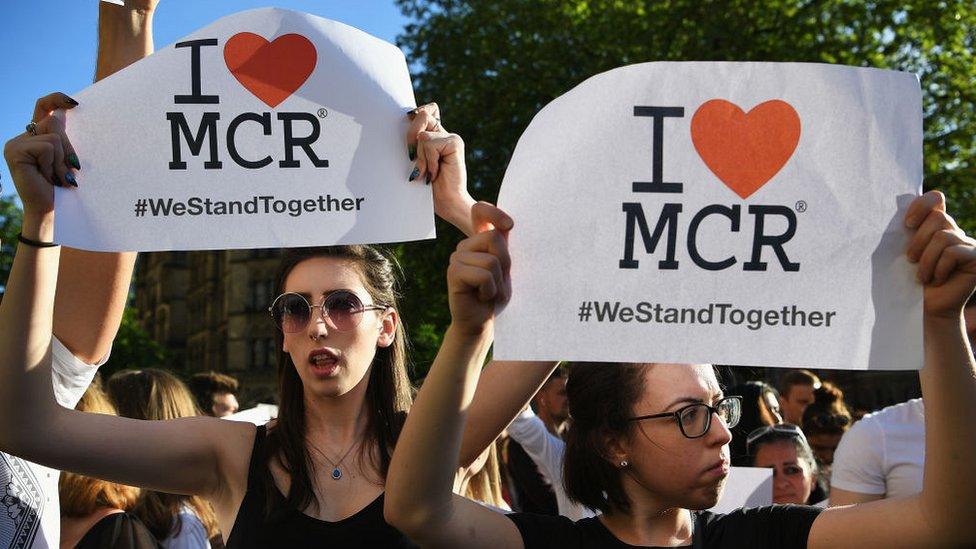 Two women hold "I love Manchester" signs at a vigil for victims of the arena attack