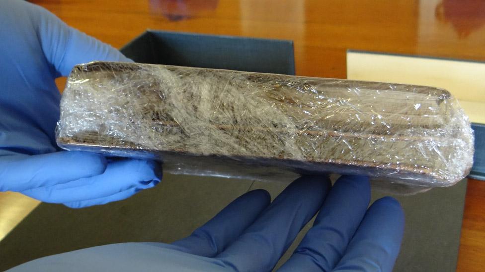 The Charles Darwin notebooks wrapped in cling film being handled by someone wearing blue rubber gloves