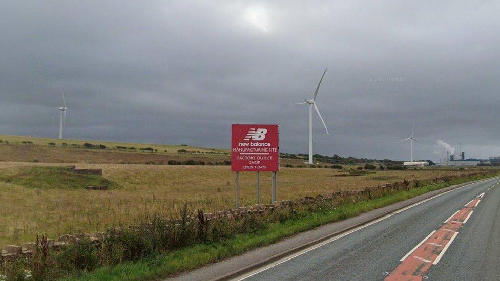 Streetview of New Balance sign with three wind turbines in the background