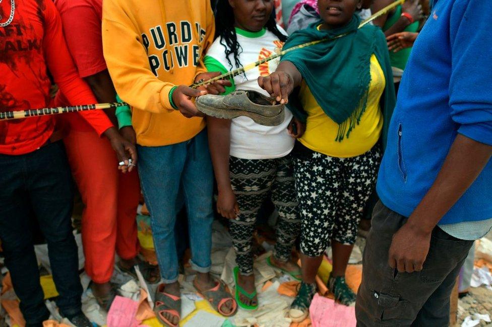 A crowd of onlookers pick up an abandoned shoe at the scene of the Precious Talent Top School collapse in Nairobi on 23 September.