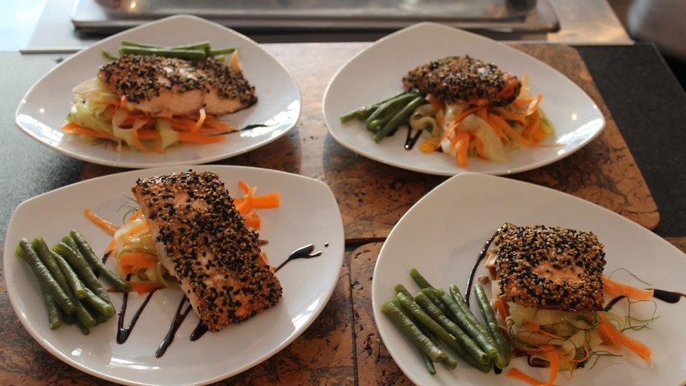 Four plates with fish and vegetables on