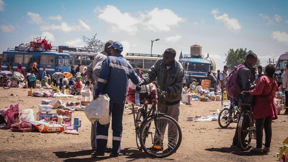 A bus station with old buses, markets traders and some people with bicycles in Asmara, Eritrea