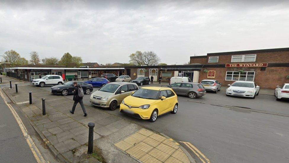 Streetview of a small shopping complex with a car park and pub