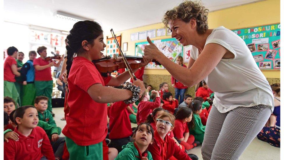 Children learning the violin in a series of workshops during the orchestra's trip to Patagonia