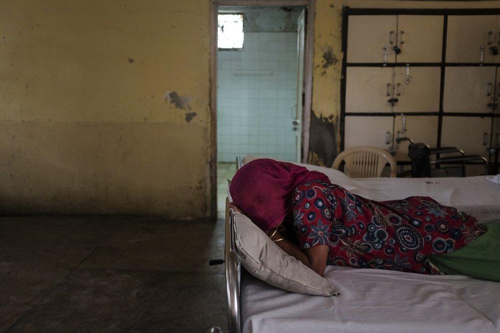 A young woman who developed psychotic symptoms after being gangraped is seen lying facedown on a bed in award at a mental health facility in Delhi. She was thrown out of her parent's home after she was diagnosed.