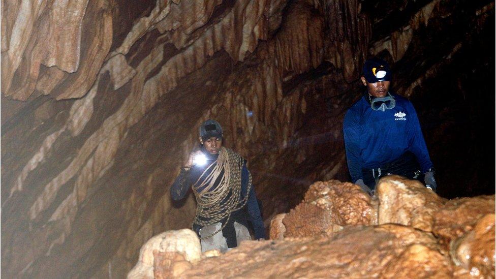 Rescue workers uses torches in their search for a football team trapped in a Thai cave