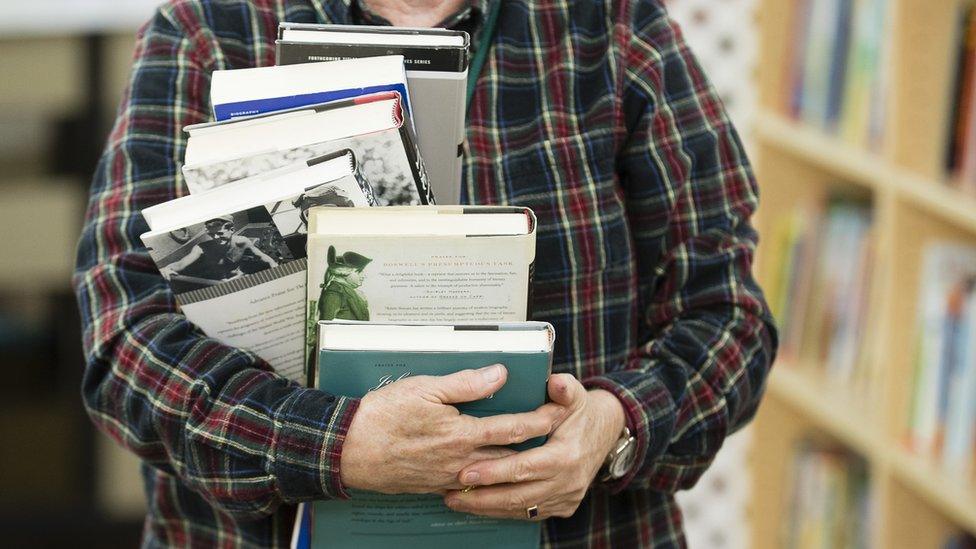 A man carrying a pile of books.