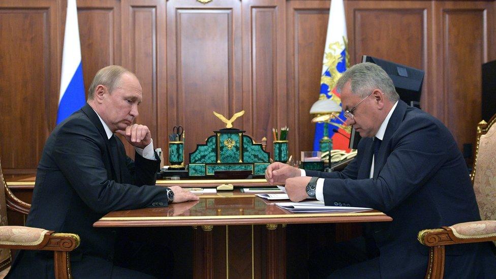 Russian president Vladimir Putin (L) listens to a report of Defence Minister Sergei Shoigu (R)