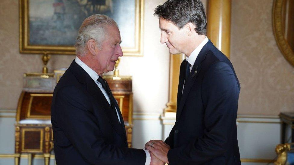 Prime Minister Justin Trudeau shakes hands with King Charles III at Buckingham Palace.