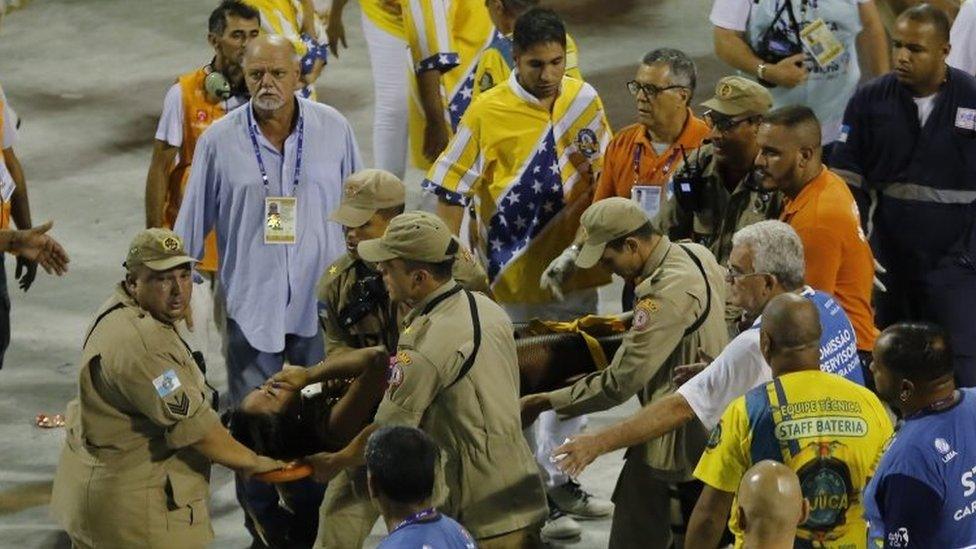 Firefighters carry an injured person on a stretcher to an ambulance during the performing of the Unidos da Tijuca samba school for the Carnival celebrations at the Sambadrome in Rio de Janeiro, Brazil, Tuesday, Feb. 28, 2017