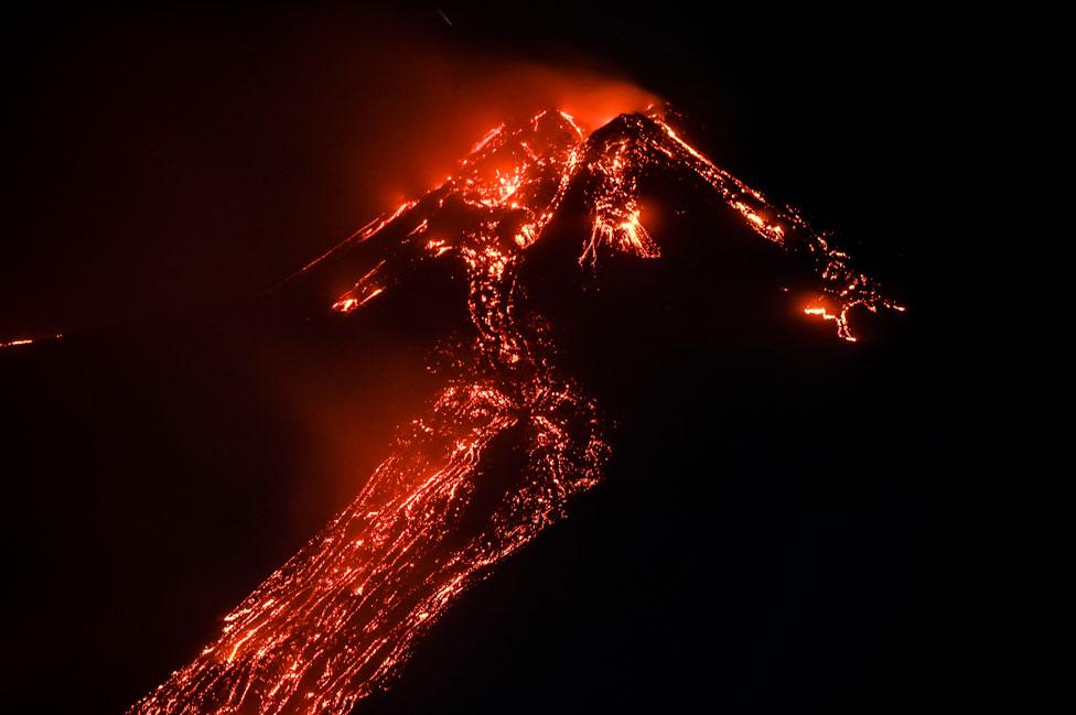 Lava flows down the side of Mount Etna at night