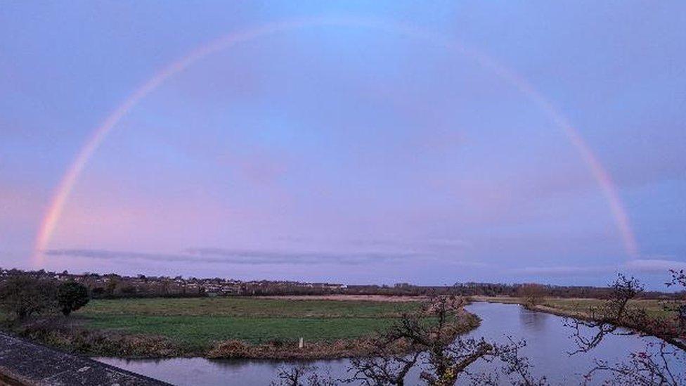 Semicircle line against a purple sky above a field and river