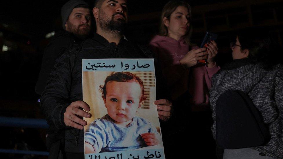 A man holds up a poster showing a victim of the Beirut port explosion, after Lebanon's public prosecutor charged the judge leading the investigation (25 January 2023)