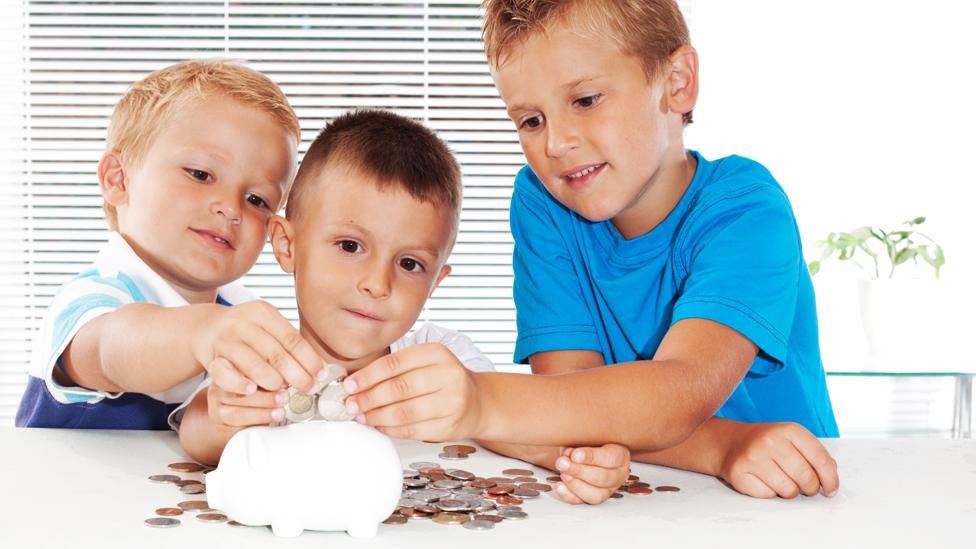 Boys putting coins into piggy bank