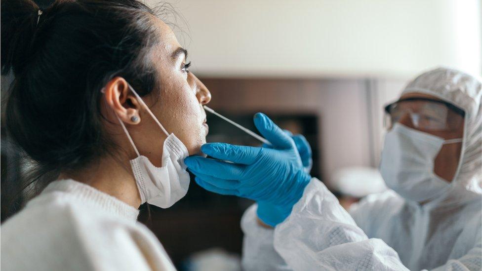 A woman takes a swab test for coronavirus