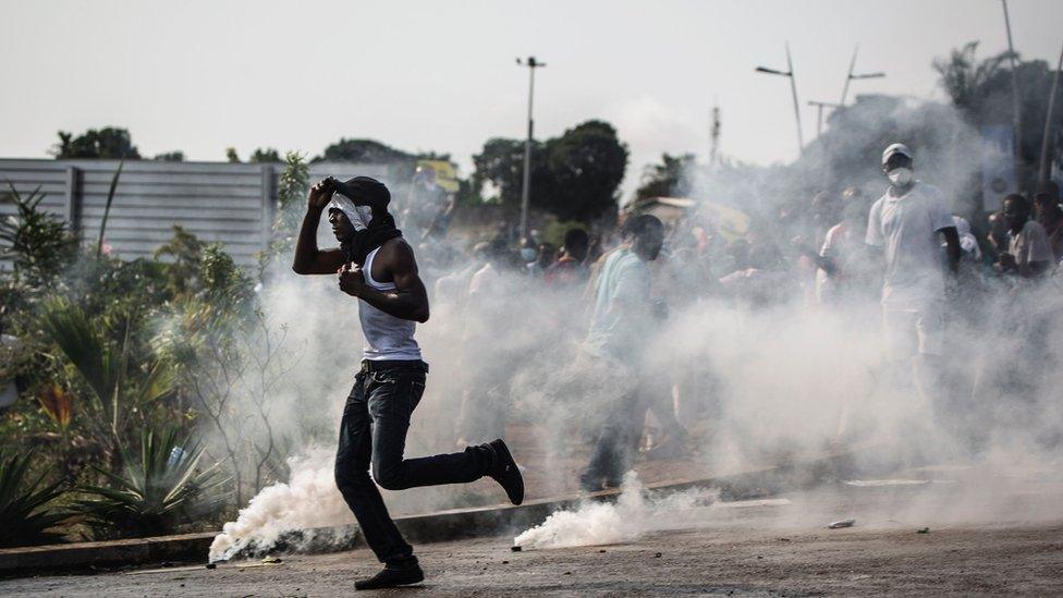 A protester runs amid tear gas canisters during confrontations with the police in Libreville, Gabon on 31 August 2016