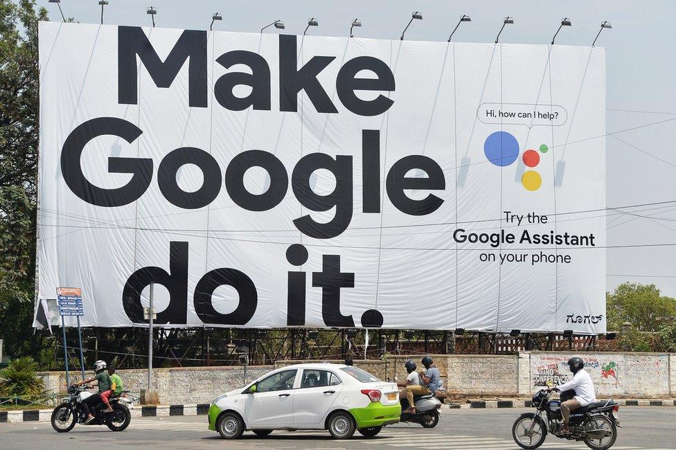 Indian commuters drive past an advertisement poster of Google in Bangalore on 6 April 2018.