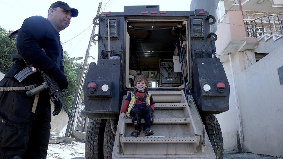 A boy sits on an Iraqi special forces vehicle in Qadsiya, Mosul