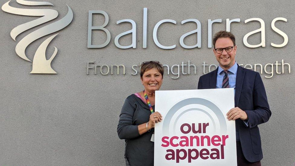 A man and a woman holding a scanner appeal sign