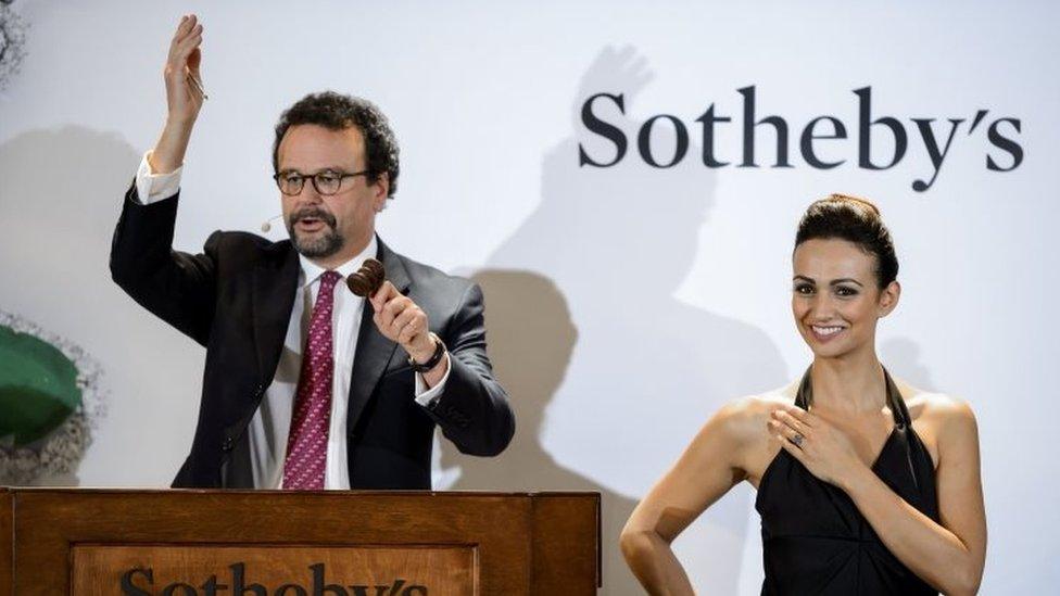 The read of Sotheby's International jewellery division (left) auctions the Blue Moon diamond which is worn by a model during Wednesday's sale (11 November 2015)