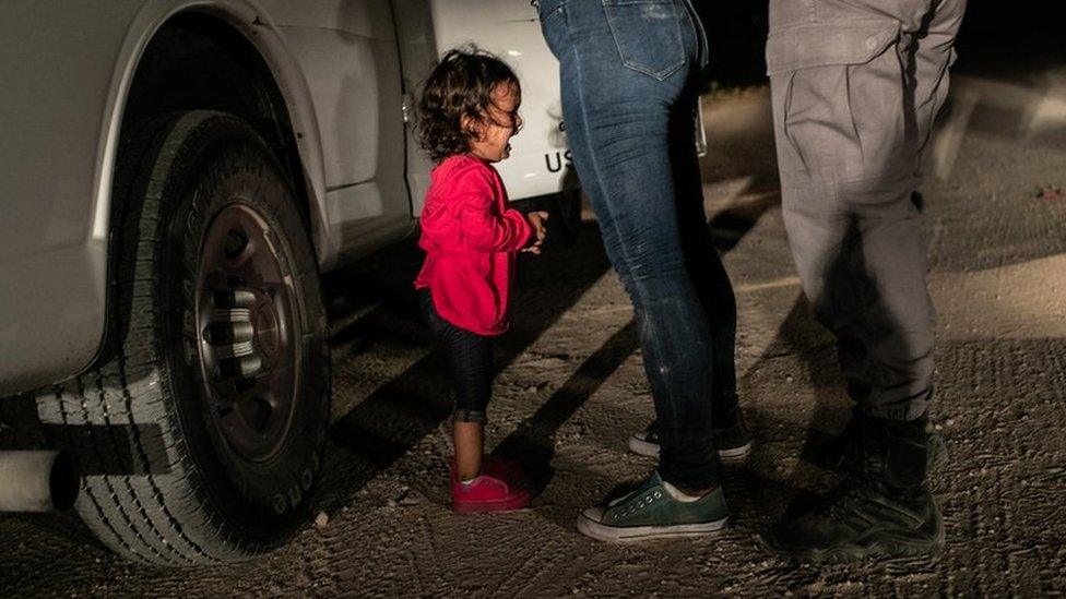 A child cries as two adults stand nearby